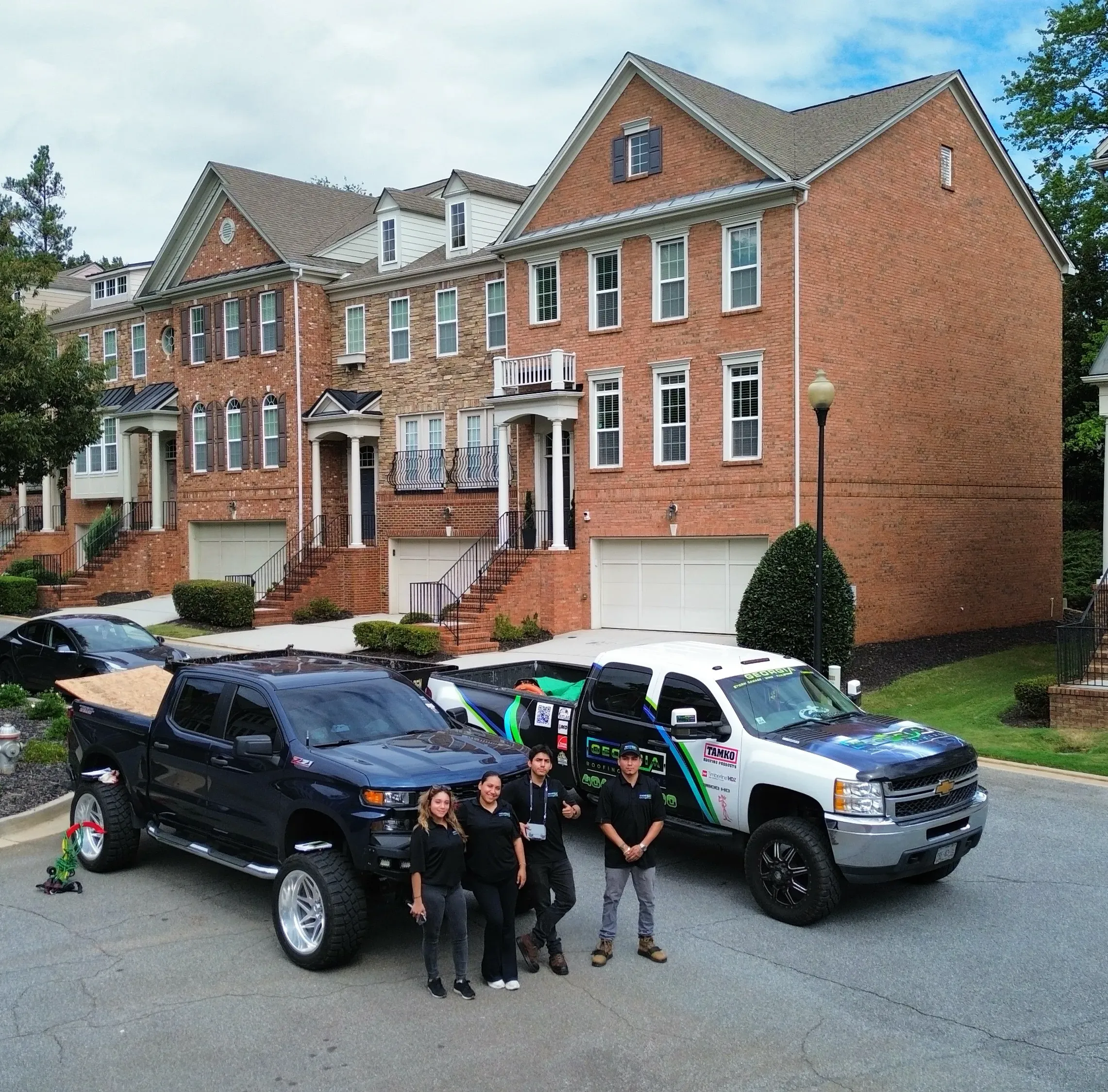 Georgia Roofing & Construction Company Team Posing for Photo in front of red brick home after a roof repair. 